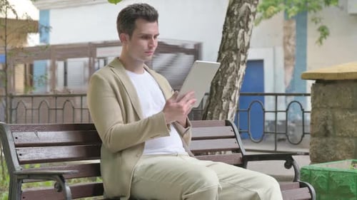 Young Adult Using Tablet on Park Bench
