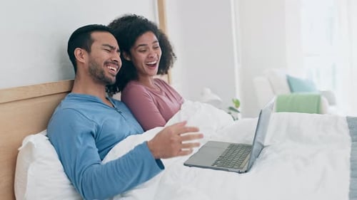 Smiling Couple in Bed with Laptop Computer
