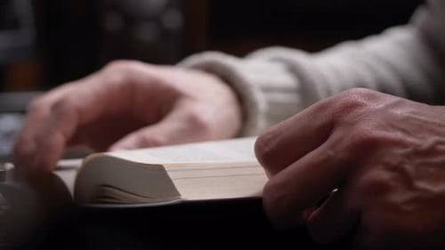 Unrecognizable person reading a book. Hand Turning Pages of a Book, close up.