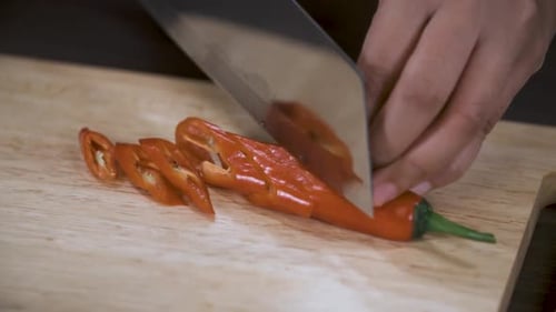 Chef Slices Red Chili Pepper on Cutting Board