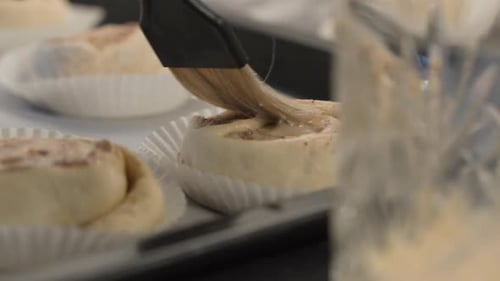 Egg stunning brushing on raw cinnamon bun dough