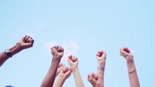 People Raise Fists in Unity Against Blue Sky
