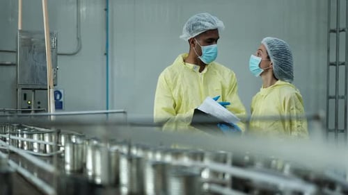Deux superviseurs industriels examinent le contrôle de la qualité de la production d'aliments en conserve.