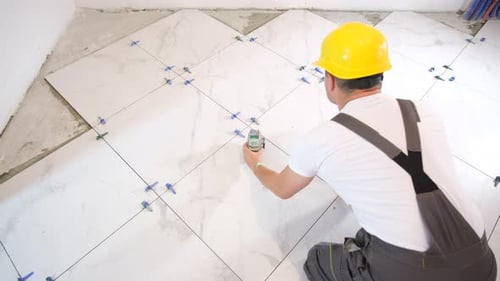 Construction Worker Installing Marble Patterned Floor Tiles