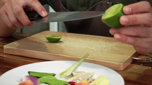 Man is Cutting Juicy Green Lime with Metal Knife on Kitchen Chopping Board Filmed in Closeup