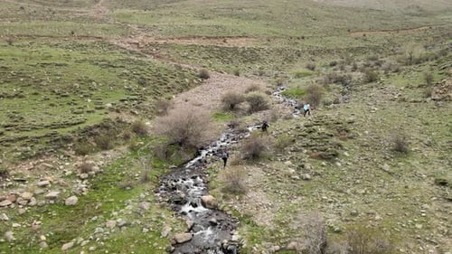 Hikers Trekking Scenic Landscape with Flowing Stream