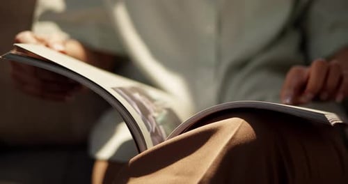 A person enjoys a moment of relaxation while flipping through a magazine in a cozy living room.