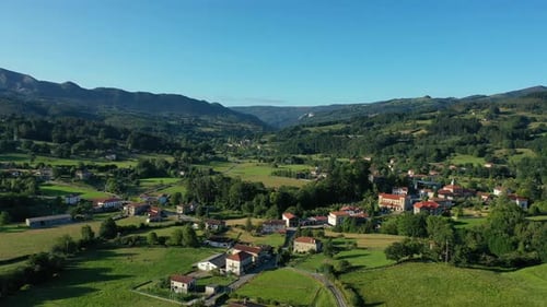 descent flight with a drone in a rural area with rustic houses spread between cultivated meadows, li