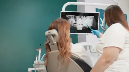 Au cabinet dentaire, la patiente examine des images détaillées de sa dentition. Le dentiste fait une
