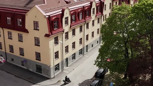 Mann fährt mit Moped in der Stadt, Drohnenschuss
