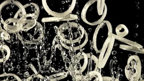 A Pile of Sliced Onion Rings with Drops of Water Soars Up and Falls Down