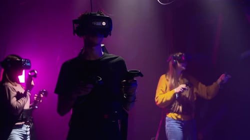 Group of people playing VR games in a studio with blue pink neon lights