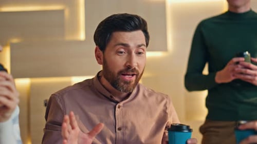 Friendly coworkers talking at coffee break in modern office enjoying funny stories