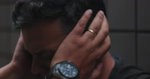 Man covering face and holding head with hands, overwhelmed by despair and emotional turmoil