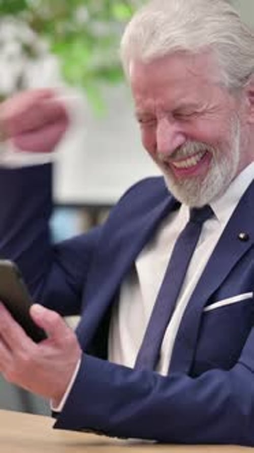 Senior Man in Suit Using Smartphone and Celebrating