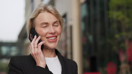 Portrait of Smiling Woman Entrepreneur Talks on Smartphone in Sunny Downtown