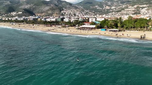 Directly Above Aerial Cinematic Shot Man on Vacation Relaxes on Stand Up Paddle Board in Turquoise