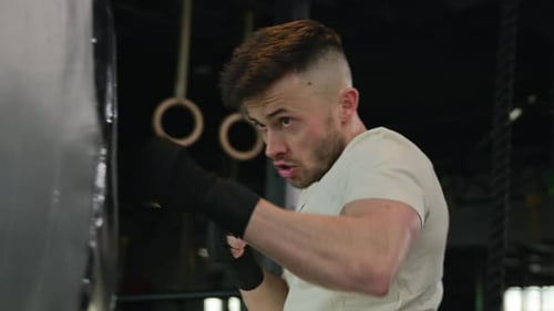 Professional Fighter Boxer Male Powerful Guy Man in Sports Gloves Boxing Punching Bag in Sport Club