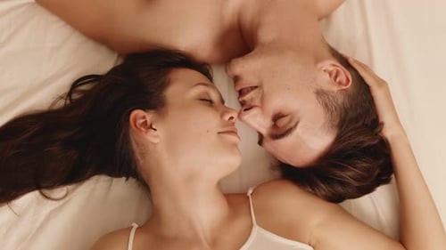 Couple amoureux s'embrassant dans son lit intime et affectueux