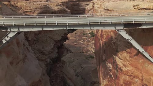 Drone pull back to reveal steel bridge over deep Utah rock canyon near Canyonlands