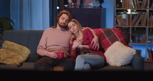 Romantic Young Millennial Adult Couple Sitting on Sofa Embracing and Talking About News Family