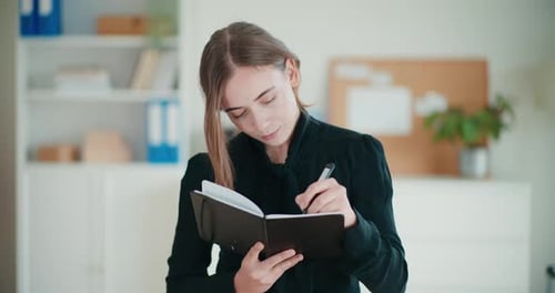 Young Woman Writing in a Notebook at Office