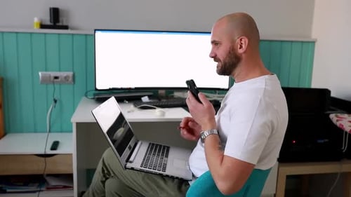 Man Working From Home With Laptop and Phone
