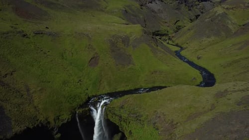 Drone footage reveals majestic waterfall cascading down rugged cliffs in Iceland, surrounded by brea