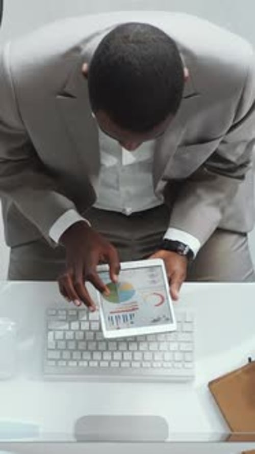 Corporate Worker Views Charts on Tablet Above Keyboard