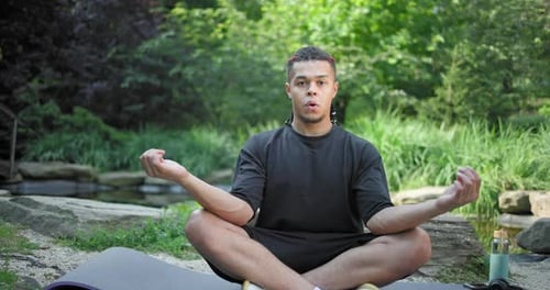 Young African American Spirituality Man Meditating Yoga Asana Sitting in a Park Outdoor