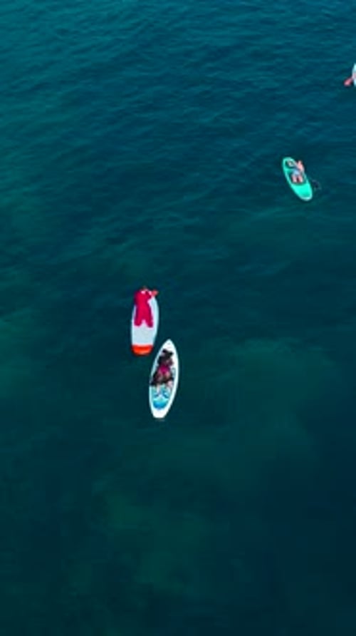 Vertical Video People Paddleboard and Relax Along the Rocky Shores of the Mediterranean Sea Under