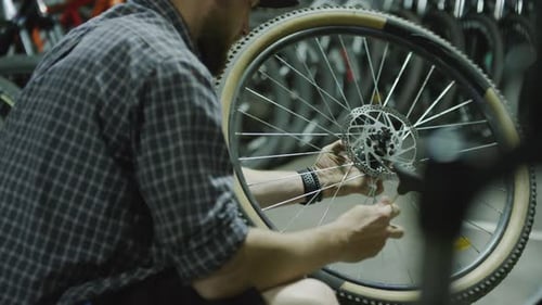 Man Repairing Bike Wheel in Garage