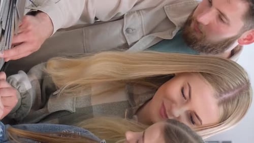 A Young Family in a Hardware Store Chooses a Wooden Laminate Surface for Home Renovation Vertical