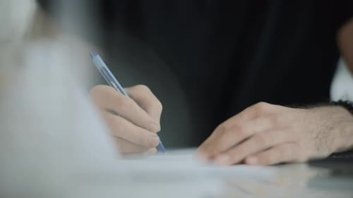 Adult writing on paper with blue pen close up