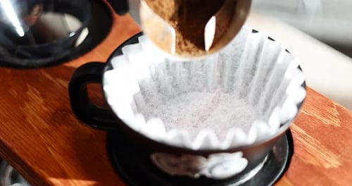 Gloved Hand Dumps Coffee Grounds into Pour-Over Filter — Golden Hour Static Shot