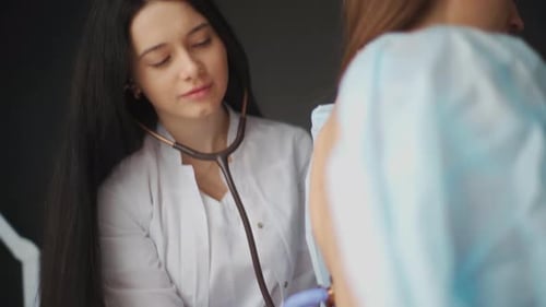 Young Adult Woman Doctor Examines Patient with Stethoscope