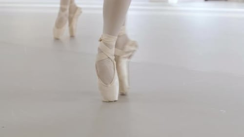 Close-up slow motion video of several ballerina's pointe shoes while practising pointe techniques in
