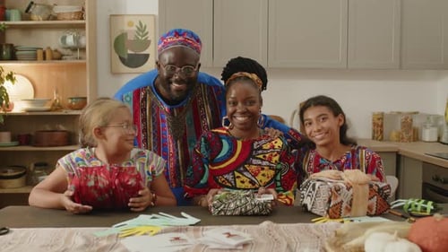 Family Smiles Together Around Table with Holiday Presents