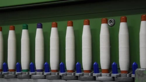 Textile Machine Winds White Thread onto Bobbins