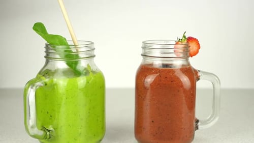 Mettre des pailles en papier dans deux smoothies aux fruits, isolés sur fond blanc