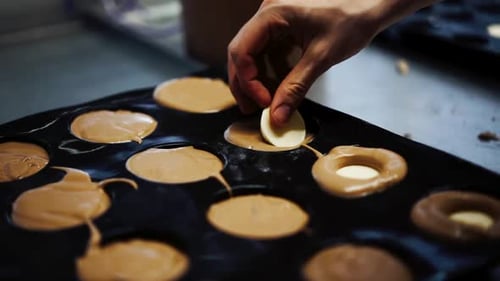 Close up shot of baker filling chocolate mix cupcakes, inserting white chocolate in the core and pre