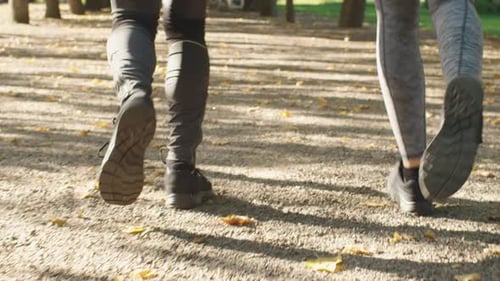 Follow Shot of Legs of Young Man and Woman Running Together at in Park at Bright Sunny Day.