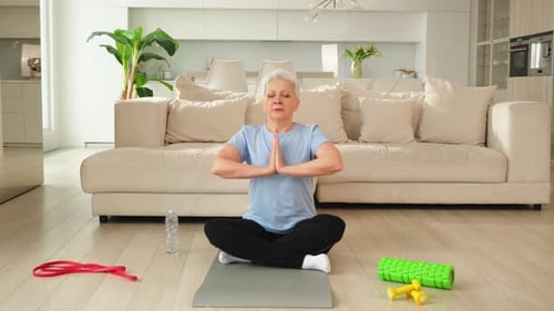 Senior Woman Meditating on Yoga Mat at Home