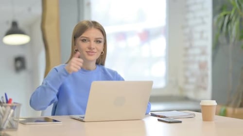 Woman Working at Laptop Gives Thumbs Up