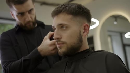 Man getting haircut by stylish barber at salon