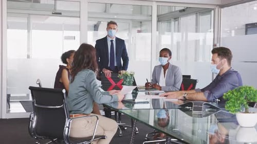 Business team meets around conference table with masks