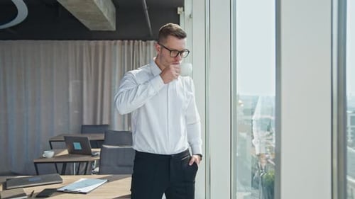 Businessman drinking coffee standing in the spacious office.