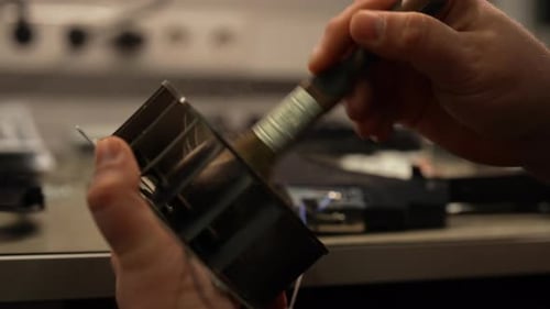 Closeup of Technician Hands Cleaning Dust and Debris From Game Console Part Using Small Brush