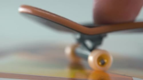 A hyper close-up detailed shot of a mini skateboard, tiny white wheels, riding fingerboard from righ