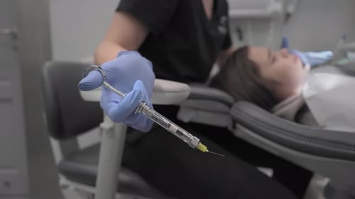 Dentist Holding Syringe Before Injection in Dental Office